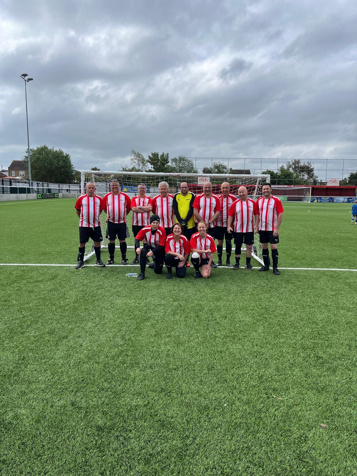 Mixed squad in red and white kit in front of the goal